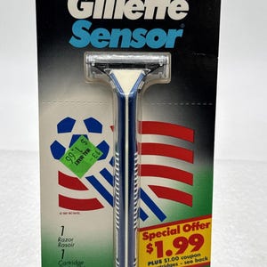 May include: Gillette Sensor razor in original packaging. The packaging features a blue and white razor with a blue and white handle. The packaging has the text "Gillette Sensor" and "WorldCupUSA94".
