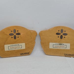 May include: Two light brown wooden basket dividers with a curved top edge and a four-petal cutout design. Each piece features a white label reading Longaberger Bread Basket Single Divider 50008 and the Longaberger Woodcrafts logo in black ink.