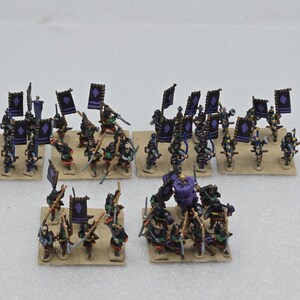 May include: A collection of miniature samurai figurines arranged in five distinct groups on square bases. The figures are painted in black and purple, featuring small rectangular banners with purple diamond symbols and various handheld weapons.
