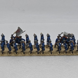 Peut inclure: Un ensemble de figurines de soldats miniatures disposées en formation rectangulaire sur une base beige. Chaque figurine porte un uniforme bleu avec un casque argenté et un fusil. Une figurine tient un drapeau blanc avec une croix rouge.