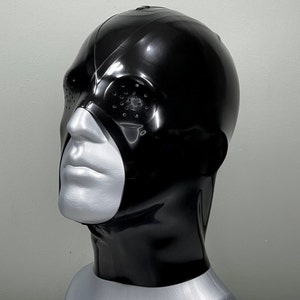 May include: A black latex mask with a single eye hole and a small, round, black opening on the side. The mask covers the head and neck.