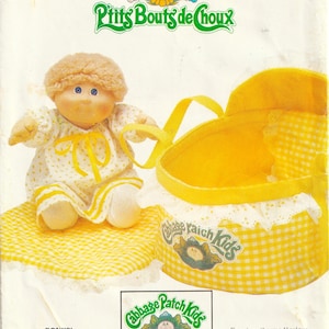 May include: A Cabbage Patch Kids sewing pattern envelope, number 6661, featuring a doll with blonde hair in a yellow and white floral dress next to a yellow gingham fabric bassinet. The Butterick brand logo is printed at the bottom of the package.