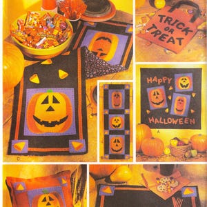 May include: A sewing pattern for Halloween decorations. The pattern includes instructions for making a table runner, a pillow, a tote bag, and a placemat. The decorations feature a pumpkin design with a happy face.