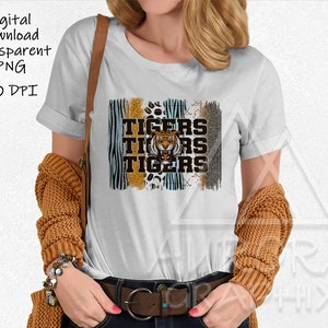 Op de afbeelding: Wit T-shirt met een grafisch ontwerp met het woord "Tigers" dat driemaal herhaald wordt, met een tijgerillustratie. Het ontwerp bevat dierenprintpatronen en een distressed effect. De woorden "Digital Download Transparent PNG 300 DPI" staan linksboven.