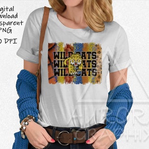 Könnte beinhalten: Weißes T-Shirt mit einem bunten Grafikdesign mit einem Tiger und dem Text "Wildcats".
