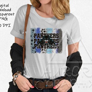 May include: White t-shirt with a blue, white and black graphic design featuring a panther with the word "Panthers" repeated three times.
