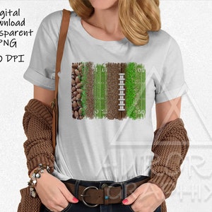 May include: A white t-shirt featuring a graphic design of a football pitch, football, and grass. The design has a distressed, vintage style.