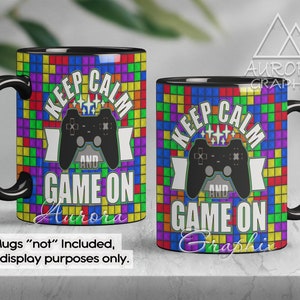 Może przedstawiać: Czarny kubek do kawy z kolorowym, pikselowanym tłem i tekstem "Keep Calm and Game On". Czarny kontroler do gier wideo znajduje się w środku wzoru.