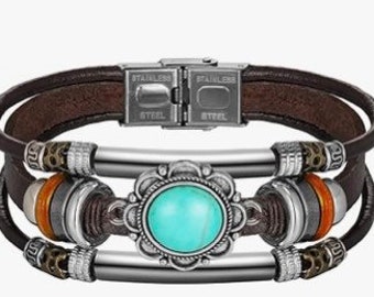 May include: A multi-layered brown leather bracelet with a turquoise stone set in a silver flower design. The bracelet has a stainless steel clasp and silver beads.