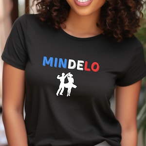 Puede incluir: Camiseta negra con la palabra "MINDELO" en letras azules, blancas y rojas. Debajo del texto, una silueta blanca de una pareja bailando. La camiseta es de un material suave.