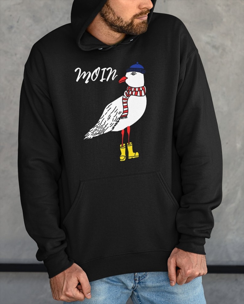 May include: Black hooded sweatshirt with a white seagull wearing a blue hat, red and white scarf, and yellow rain boots. The text "moin" is printed on the sweatshirt.