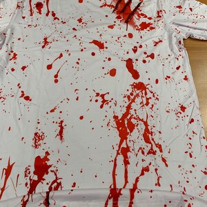 May include: White t-shirt with red splattered paint and claw marks. The shirt is a Halloween costume.