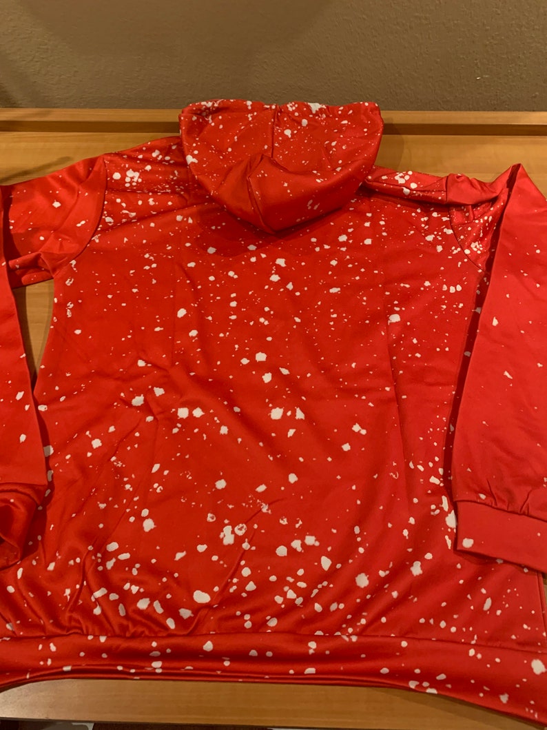 K&ouml;nnte beinhalten: Roter Kapuzenpullover mit einem wei&szlig;en Spr&uuml;hfarben-Design.