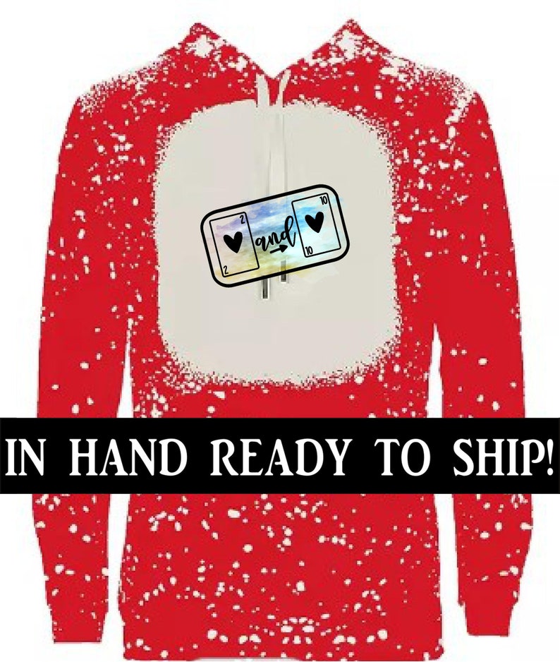 K&ouml;nnte beinhalten: Roter Hoodie mit einem wei&szlig;en Spritzmuster. Der Hoodie hat eine wei&szlig;e K&auml;ngurutasche mit einer Grafik von zwei Spielkarten, einer 2 Herz und einer 10 Herz, mit dem Wort "and" dazwischen.