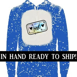 May include: Blue hoodie with a white splatter pattern and a graphic of two playing cards with hearts and the word "and" on them.