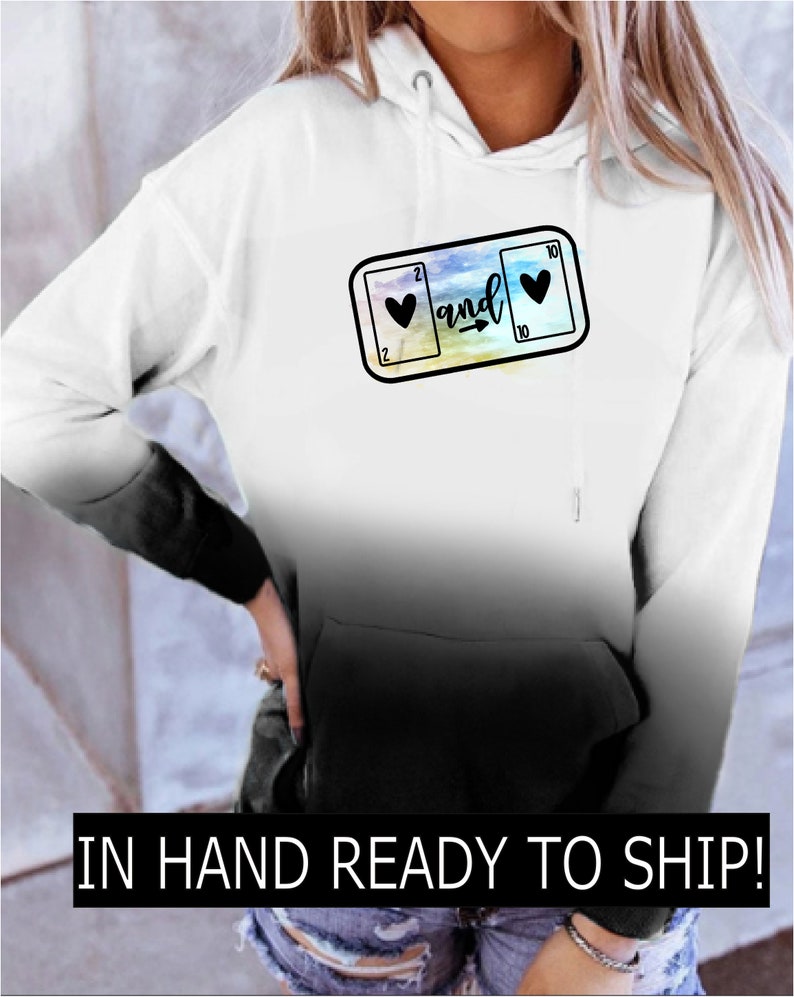 May include: White ombre hoodie with a black graphic of two playing cards, a 2 of hearts and a 10 of hearts, with the word "and" and an arrow between them.