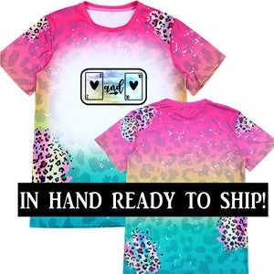May include: Pink and blue ombre t-shirt with a leopard print design. The shirt features a graphic of a slot machine with hearts and the word "and".