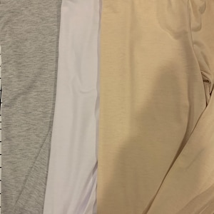 May include: Three long-sleeved shirts in different colors: gray, white, and beige.