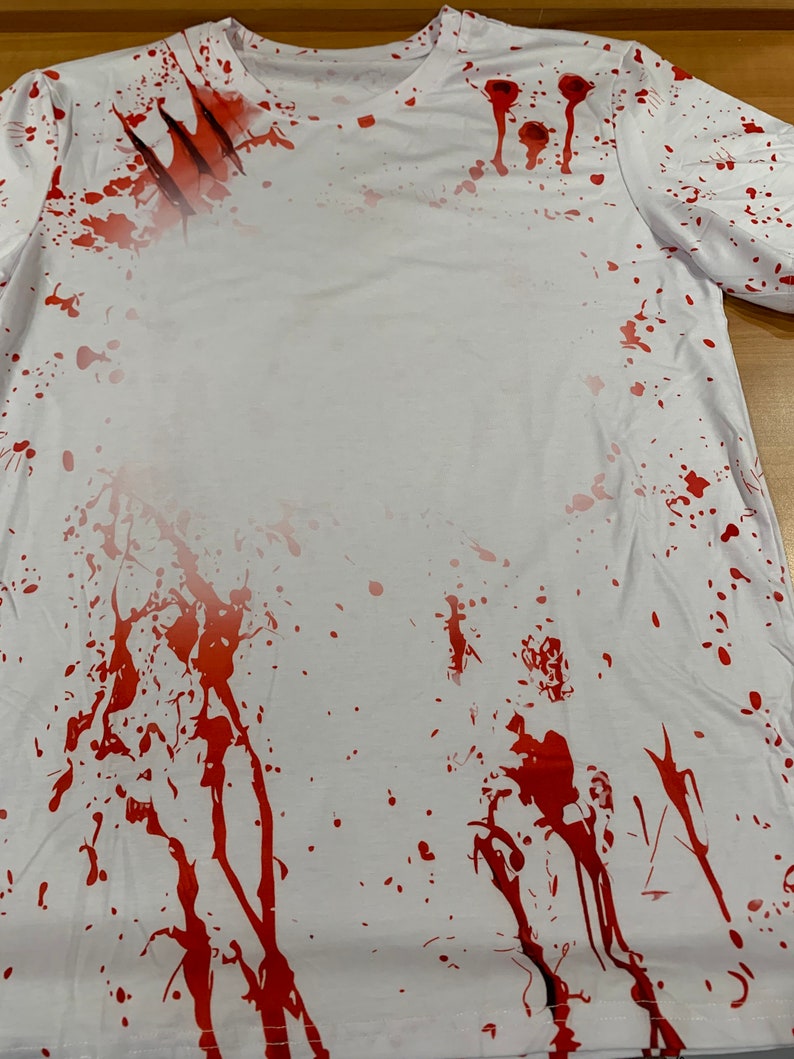 May include: White t-shirt with red splattered paint and claw marks. The shirt has a distressed look.