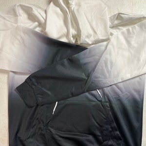 May include: A white and black ombre hoodie with a drawstring hood and a kangaroo pocket.