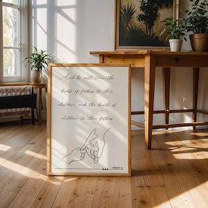 May include: A framed print with a light wood frame, featuring the text "And he will turn the hearts of fathers to their children and the hearts of children to their fathers." The print includes a line drawing of two hands holding each other.