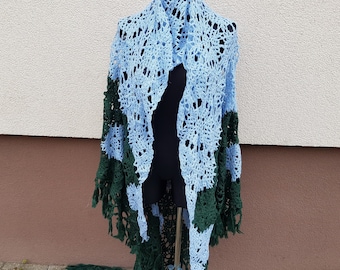 Puede incluir: Un chal de ganchillo con un patrón de color azul y verde. El chal tiene un borde de flecos y se muestra en un maniquí.