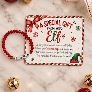 May include: A red beaded bracelet with white letter beads spelling EMMA, displayed next to a rectangular card featuring a red bow, green elf hat, and the text A SPECIAL GIFT FROM YOUR ELF, A merry little bracelet from your elf today.