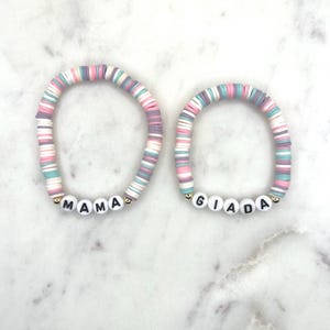 May include: Two colourful beaded bracelets with the names "MAMA" and "GIADA" spelled out in black letters on white beads.