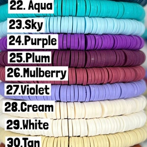 May include: A close-up of 16 different colours of round polymer clay beads. The beads are stacked on top of each other, with the colours labelled from 19 to 34. The colours include navy, royal blue, marine, aqua, sky, purple, plum, mulberry, violet, cream, white, tan, brick, grey, slate, and black.