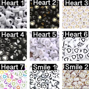 May include: Assortment of white, black and gold heart-shaped beads with black, white and gold smiley face beads.