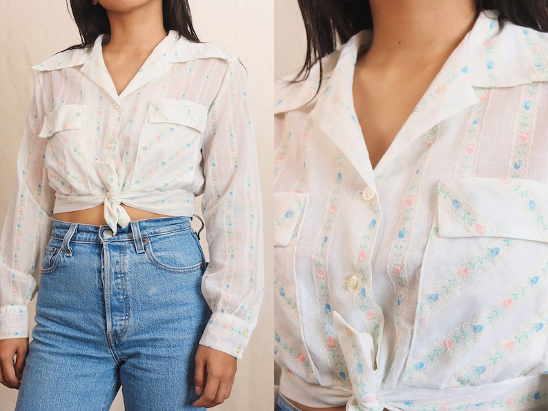 May include: White button-up shirt with long sleeves, two chest pockets, and a tie-front closure. The shirt features a vertical striped pattern with small pink and blue floral accents. The collar is a classic style.