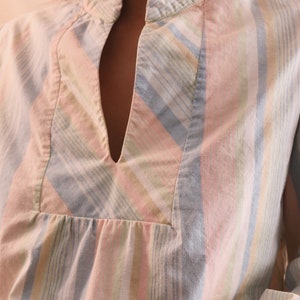 Peut inclure: Chemise &agrave; rayures pastel avec col officier et encolure en V. La chemise pr&eacute;sente des rayures verticales roses, bleues, jaunes et blanches. Le tissu semble &ecirc;tre un m&eacute;lange l&eacute;ger de coton ou de lin.
