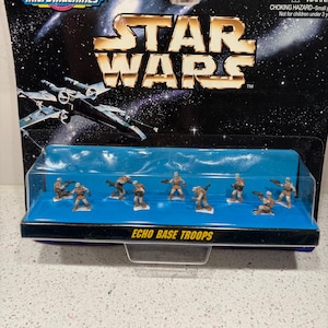 May include: A Micro Machines Star Wars Echo Base Troops set in original packaging. The blister pack contains eight small, tan-coloured soldier figurines on a blue base, set against a black space-themed card with a gold Star Wars logo.