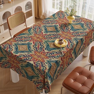 Pode incluir: Uma toalha de mesa retangular com um padrão geométrico colorido em tons de azul, vermelho, amarelo e bege. A toalha cobre uma mesa, com um prato pequeno com uma sobremesa em cima.