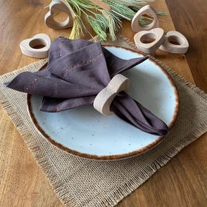 May include: Set of wooden heart-shaped napkin rings. The rings are made of natural wood and have a rustic look. They are perfect for adding a touch of elegance to any table setting.