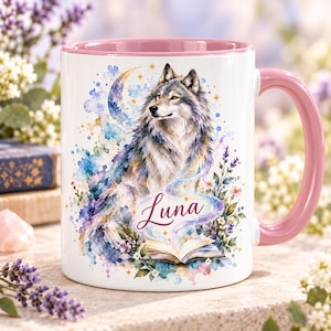 May include: A white ceramic mug with a pink interior and handle, featuring a watercolour illustration of a grey wolf, a crescent moon, stars, flowers, and an open book. The name Luna is written in a cursive script across the centre of the design.