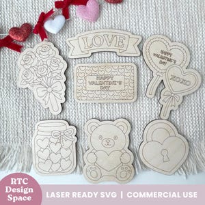 Könnte beinhalten: Eine Sammlung lasergeschnittener Holzdekorationen zum Valentinstag. Das Set enthält einen Rosenstrauß, ein Glas voller Herzen, einen Teddybären mit einem Herz, ein herzförmiges Schloss und Schilder mit den Worten "LOVE", "HAPPY VALENTINE'S DAY" und "XOXO".