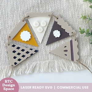 May include: A string of pie-shaped pennants in various colors, including yellow, white, and brown, with decorative elements. Each pennant has a scalloped edge and is strung together with twine. The text "RTC Design Space" and "LASER READY SVG | COMMERCIAL USE" are visible.