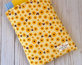 May include: A yellow book sleeve with a floral pattern of yellow sunflowers and red butterflies. The sleeve has a sewn-on label that reads "Darula Designs Handmade".