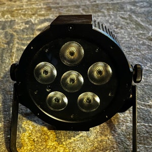 May include: Black stage light with a round head and a metal stand. The light has seven round LED bulbs.