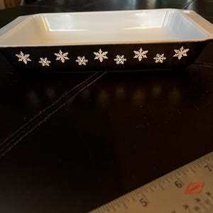 May include: Black rectangular baking dish with a white snowflake design around the rim.