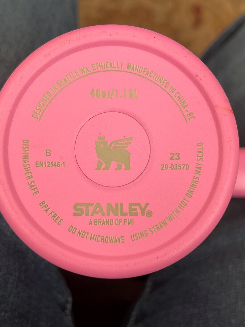 May include: A pink Stanley brand tumbler base with the text "40oz/1.18L". The base includes the text "Designed in Seattle WA, Ethically Manufactured in China-BC". The base also includes the text "Dishwasher Safe BPA Free Do Not Microwave Using Straw With Hot Drinks May Scald".