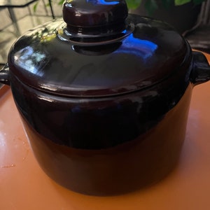 May include: A dark brown ceramic crock pot with a lid. The crock pot has a smooth, glossy finish.