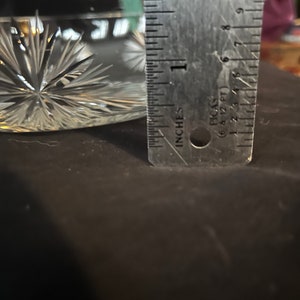 May include: A clear glass bowl with a starburst pattern. The bowl is approximately 2 inches in diameter.