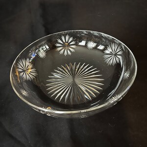 May include: A clear glass bowl with a starburst pattern etched into the bottom and around the rim.