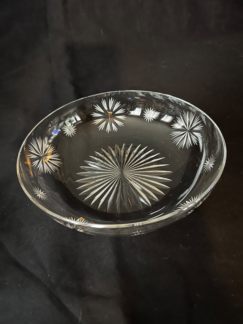 May include: A clear glass bowl with a starburst pattern etched into the bottom and around the rim.