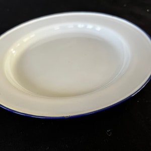 May include: White enamel dinner plate with a blue rim.