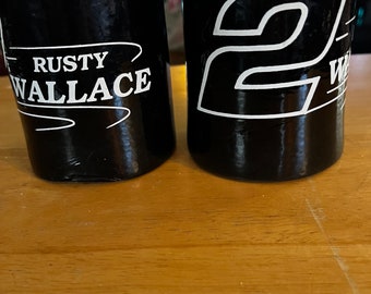 May include: Two black insulated beverage holders. One has the name "Rusty Wallace" printed in white. The other has the number "2" printed in white.