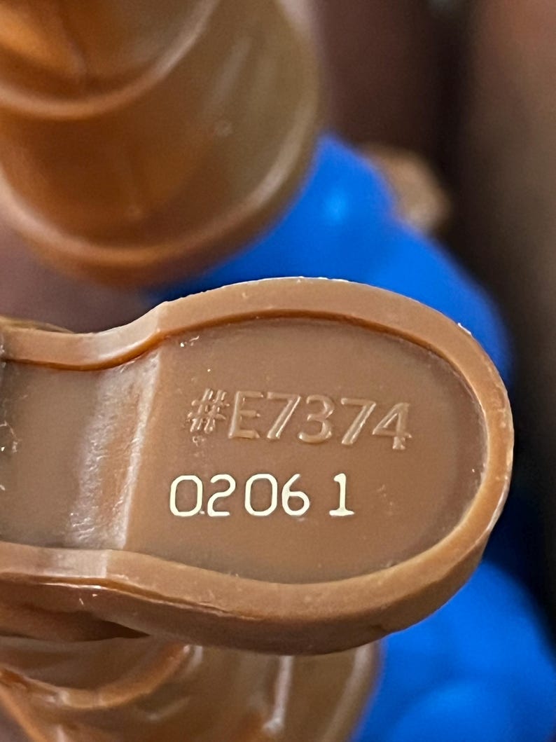 May include: Close-up of a brown plastic toy with the number "#E7374" and "0206 1" printed on it.
