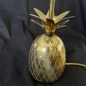 Puede incluir: Una lámpara de mesa de piña dorada con un diseño de rombos.